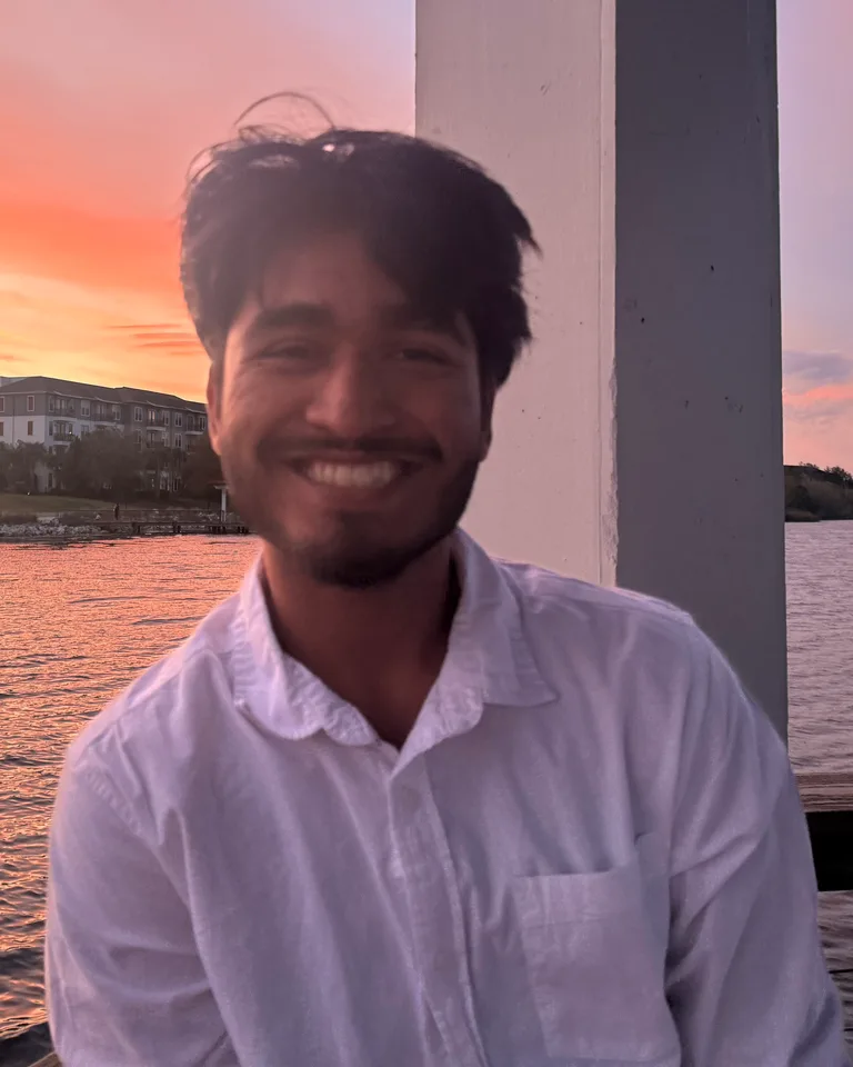 Shade Rahman, smiling, by the water at sunset